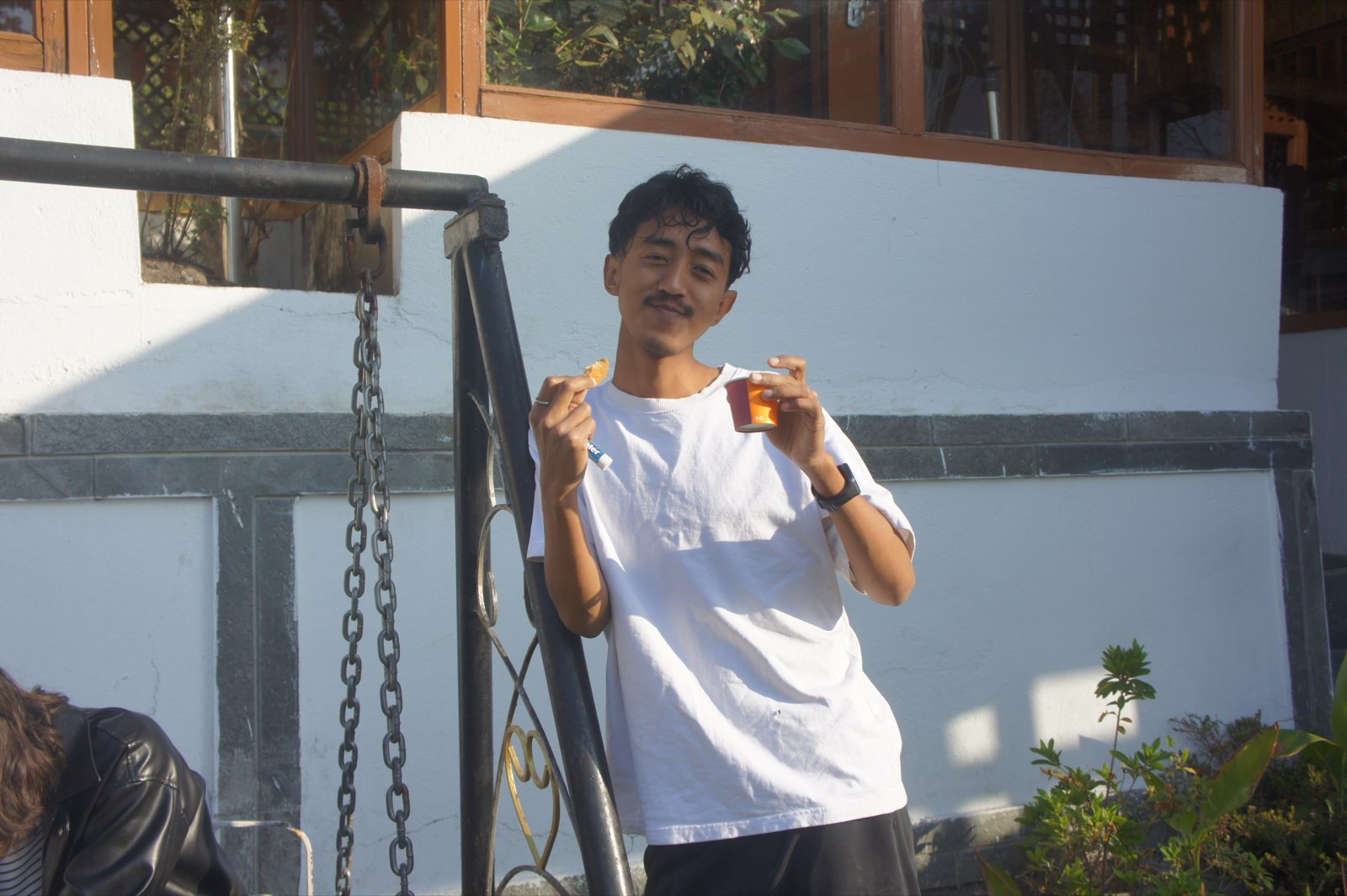 A student pauses for a snack beside the garden swing during a college outing